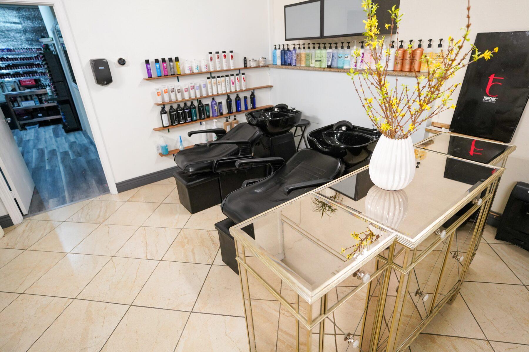 Shampoo stations beside a mirrored gold table and a vase of yellow forsythia